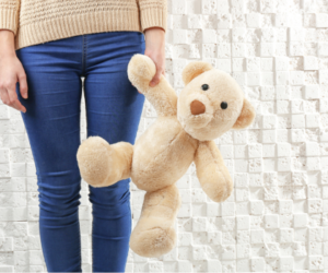 a child from the waist down standing and holding a teddy bear by the arm
