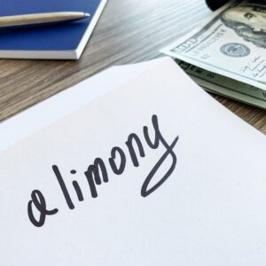 Paper with the word alimony written on it with money and paper on a table