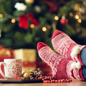 Christmas cup on table with someone's feet on the table with holidays socks on.