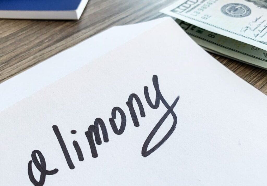 Paper with the word alimony written on it with money and paper on a table