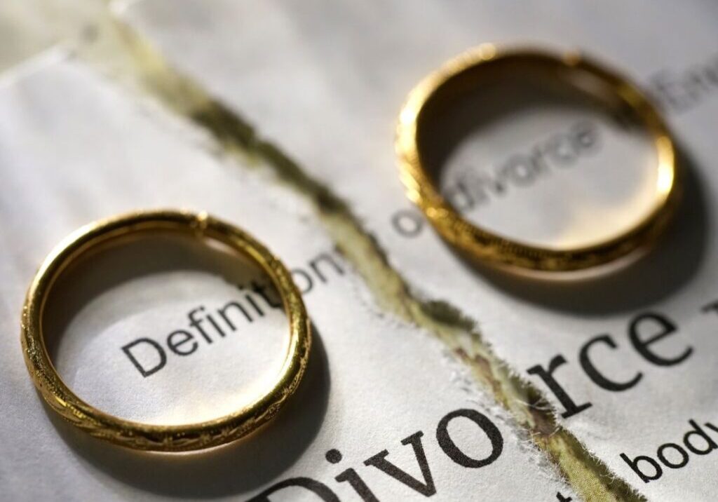 Divorce decree split in half with a ring on either side of the paper.